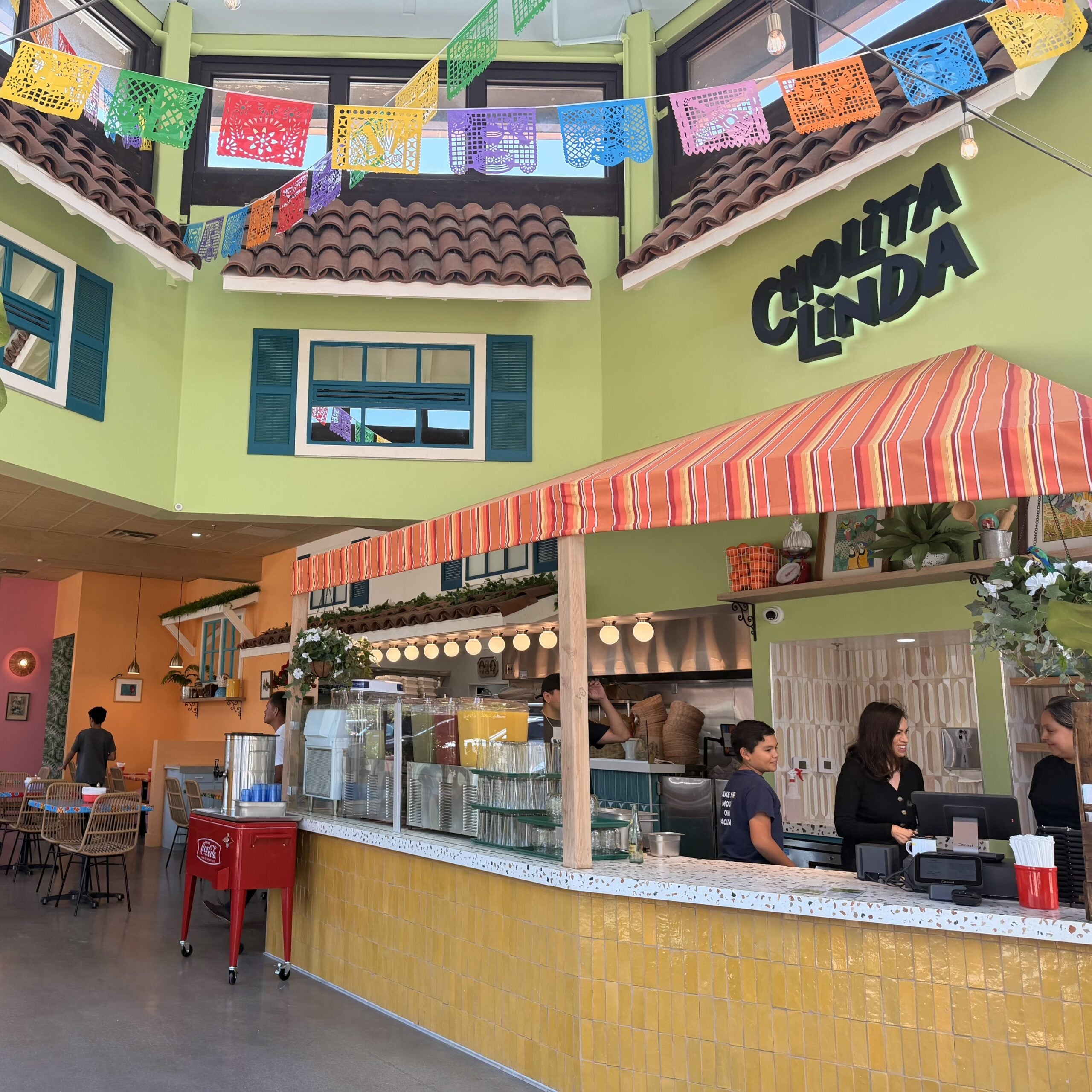 Cholita Linda dining room with colorful walls, counter seating, dining room tables and seating and high ceilings Light-filled courtyard dining area with wood tables and open glass doors